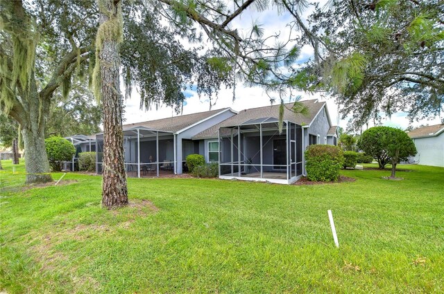 back of property featuring a sunroom, a lawn, and a lanai