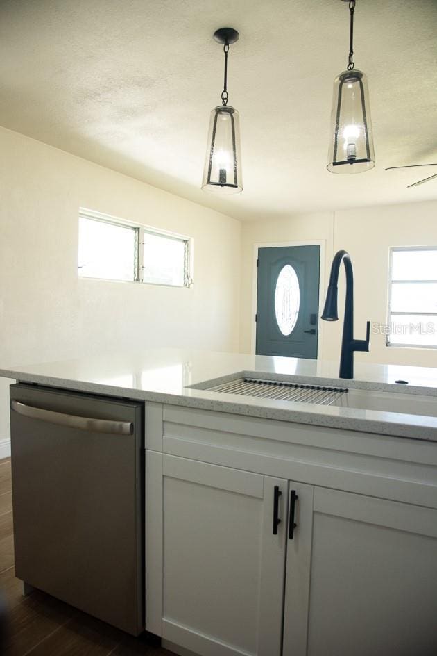 kitchen featuring sink, dishwasher, decorative light fixtures, and dark hardwood / wood-style flooring