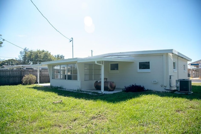 rear view of property featuring central AC, a sunroom, and a lawn