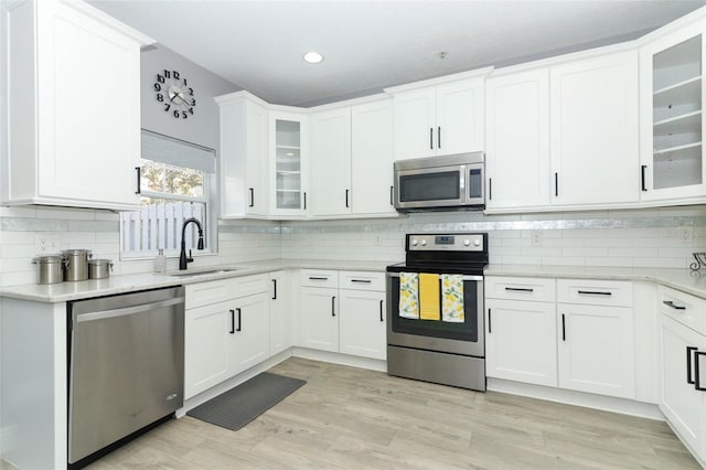 kitchen featuring stainless steel appliances, decorative backsplash, white cabinetry, and sink