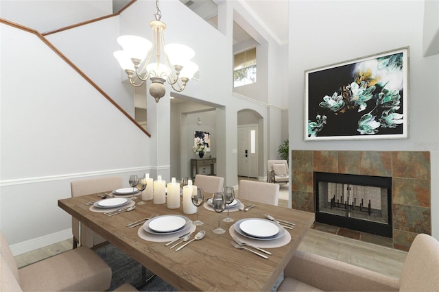 dining room with a towering ceiling, a tile fireplace, and a notable chandelier