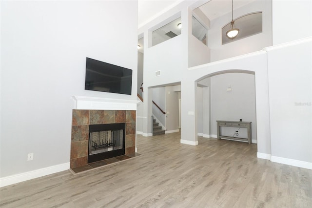 unfurnished living room featuring hardwood / wood-style floors, a towering ceiling, and a fireplace