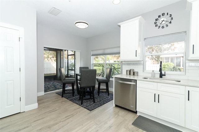 kitchen with tasteful backsplash, dishwasher, sink, white cabinetry, and light wood-type flooring