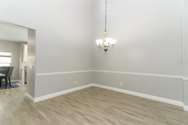 spare room featuring a chandelier and light wood-type flooring