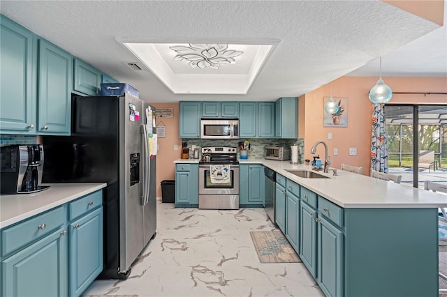 kitchen featuring kitchen peninsula, hanging light fixtures, backsplash, sink, and stainless steel appliances