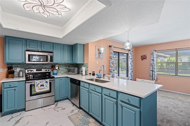 kitchen featuring kitchen peninsula, sink, pendant lighting, appliances with stainless steel finishes, and a textured ceiling