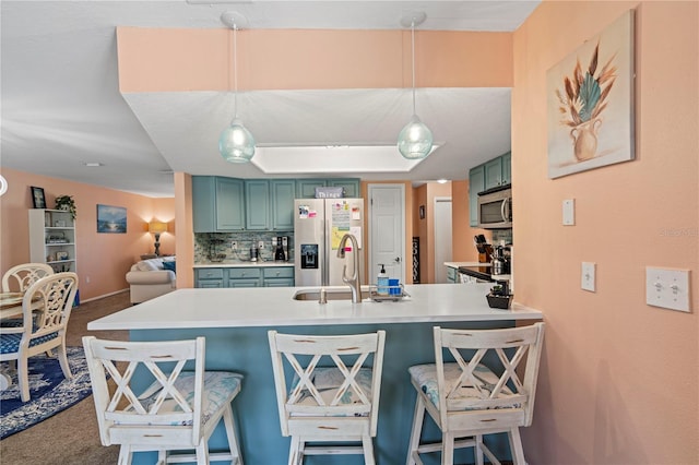 kitchen featuring a breakfast bar area, carpet floors, stainless steel appliances, and pendant lighting