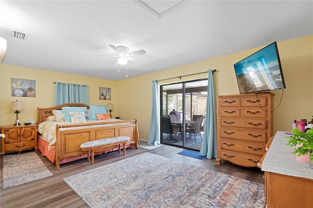 bedroom featuring a textured ceiling, dark hardwood / wood-style floors, access to outside, and ceiling fan