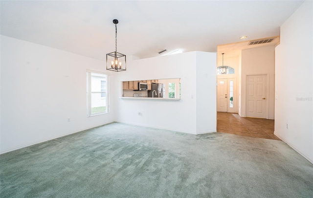 unfurnished living room featuring a notable chandelier and carpet floors