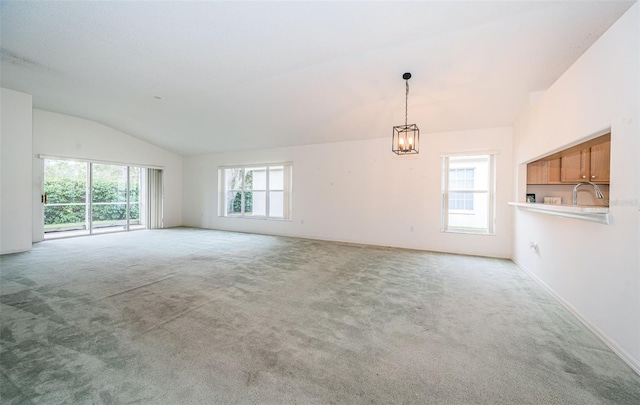 carpeted spare room featuring lofted ceiling, sink, and a notable chandelier