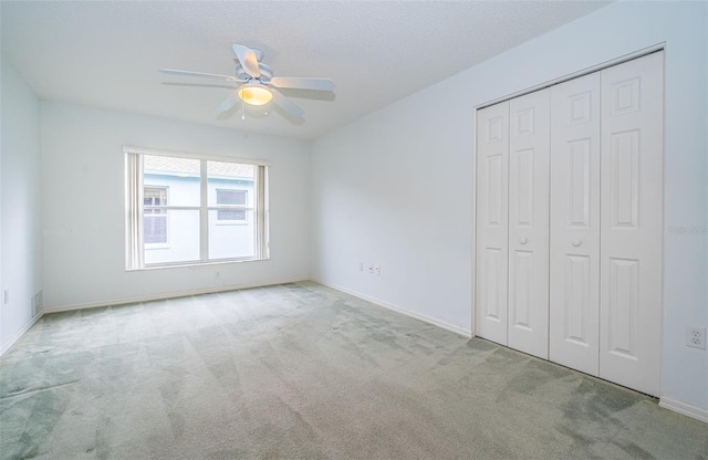 unfurnished bedroom featuring ceiling fan, light colored carpet, a closet, and a textured ceiling