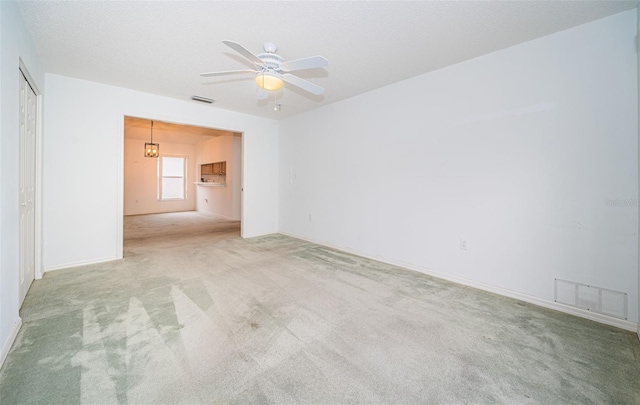 unfurnished room featuring ceiling fan, light carpet, and a textured ceiling