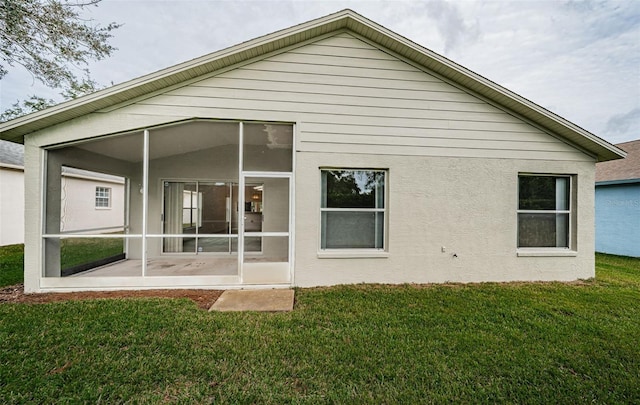 back of house with a sunroom and a lawn