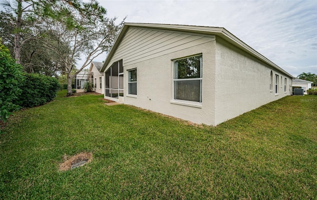 view of property exterior featuring central AC unit and a lawn