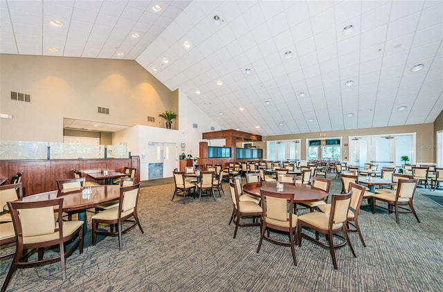 dining room featuring high vaulted ceiling and carpet