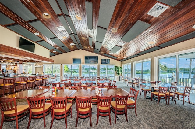 carpeted dining room featuring a healthy amount of sunlight, high vaulted ceiling, and wooden ceiling