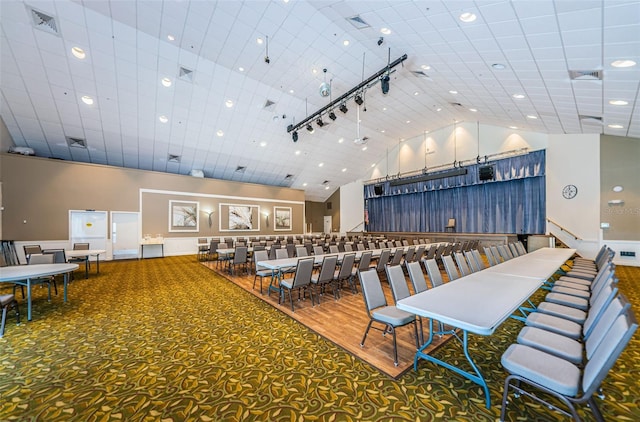 dining area with track lighting, carpet flooring, and high vaulted ceiling