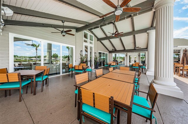 sunroom featuring lofted ceiling with beams, ceiling fan, and ornate columns