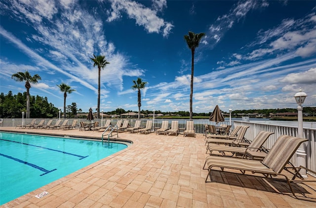 view of swimming pool featuring a water view and a patio area