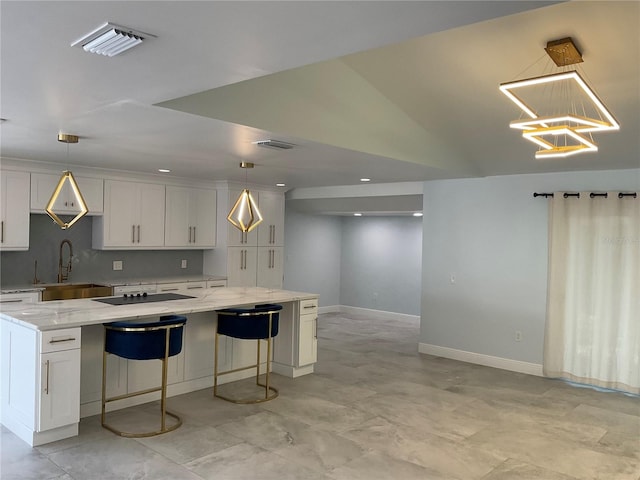 kitchen with light stone counters, decorative light fixtures, and white cabinets