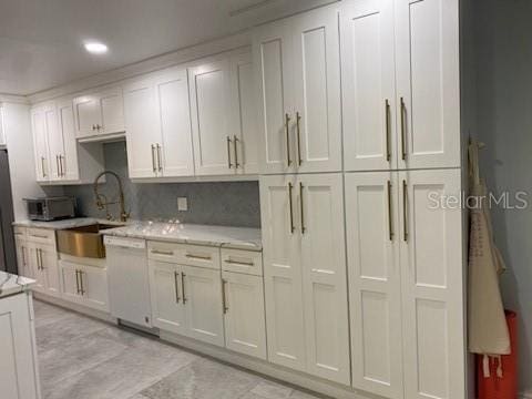 kitchen featuring tasteful backsplash, white dishwasher, sink, and white cabinets