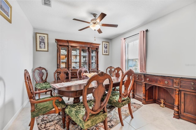 tiled dining room with ceiling fan and a textured ceiling