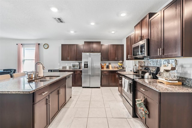 kitchen featuring a textured ceiling, light tile patterned flooring, sink, dark brown cabinetry, and stainless steel appliances