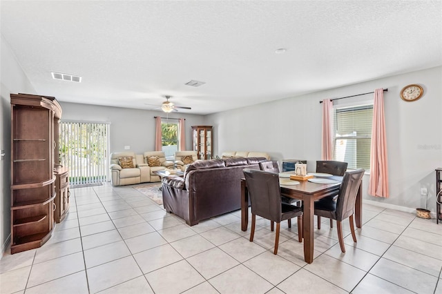 dining area with a textured ceiling, light tile patterned floors, and ceiling fan