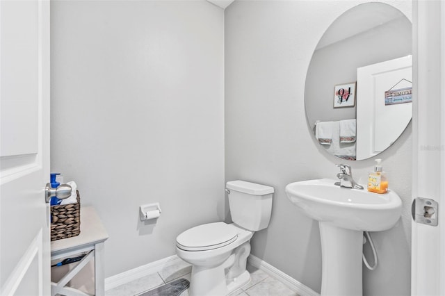 bathroom with toilet, sink, and tile patterned flooring