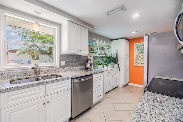 kitchen with white cabinetry, stainless steel appliances, light stone countertops, and sink