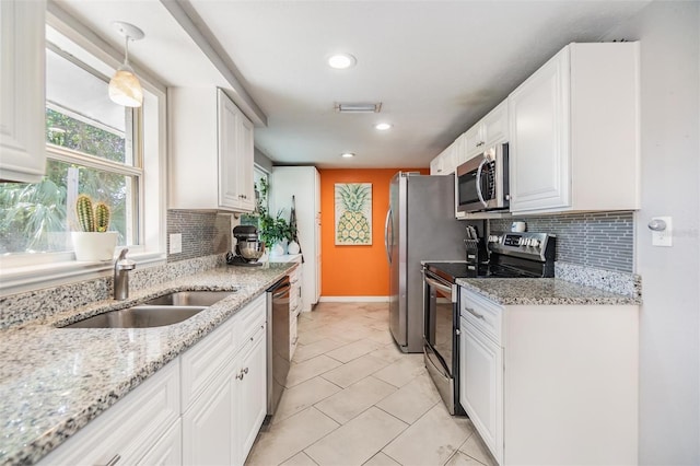 kitchen featuring sink, appliances with stainless steel finishes, light stone counters, and white cabinets