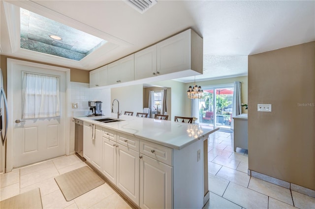 kitchen featuring sink, kitchen peninsula, decorative light fixtures, white cabinets, and light tile patterned floors