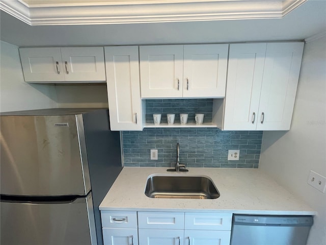 kitchen featuring decorative backsplash, white cabinets, stainless steel appliances, and sink