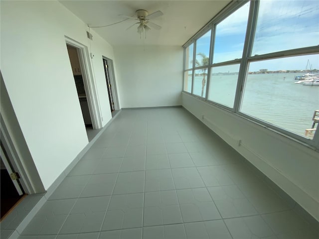 unfurnished sunroom with a water view and ceiling fan