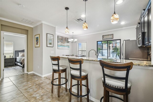 kitchen featuring ornamental molding, a breakfast bar, light stone countertops, and hanging light fixtures