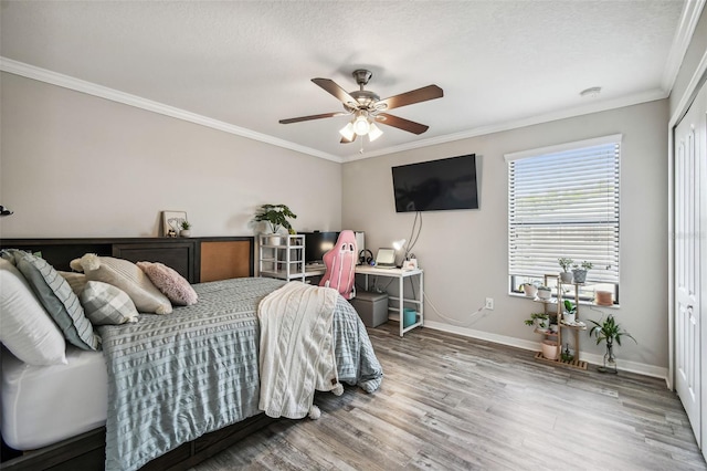 bedroom featuring ornamental molding, wood-type flooring, a closet, and ceiling fan