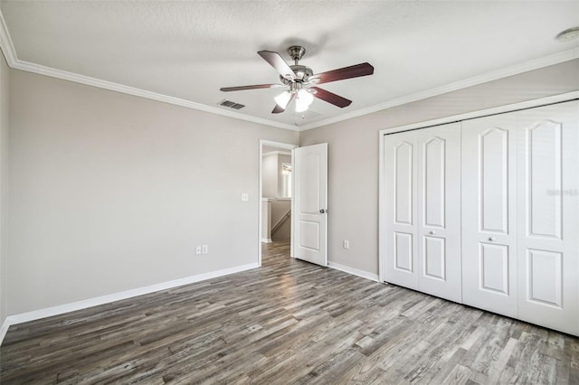 unfurnished bedroom featuring a closet, ornamental molding, hardwood / wood-style floors, a textured ceiling, and ceiling fan