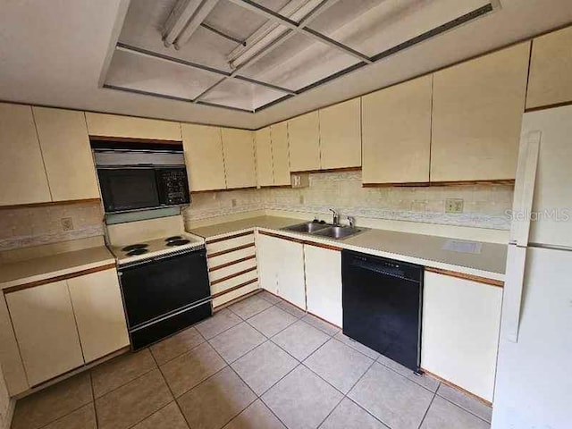 kitchen with decorative backsplash, cream cabinetry, sink, black appliances, and light tile patterned floors