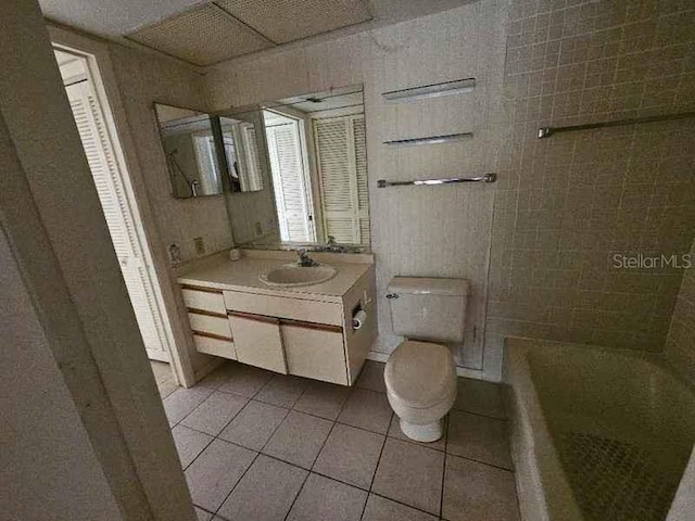 bathroom with toilet, vanity, and tile patterned flooring