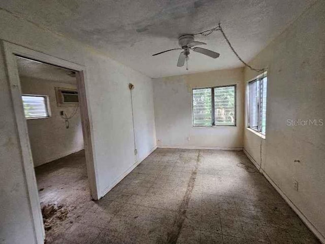 empty room featuring a wall mounted AC and ceiling fan