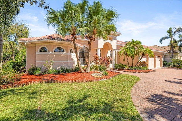 mediterranean / spanish-style home featuring a front lawn and a garage