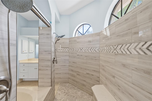 bathroom with a tile shower and vanity