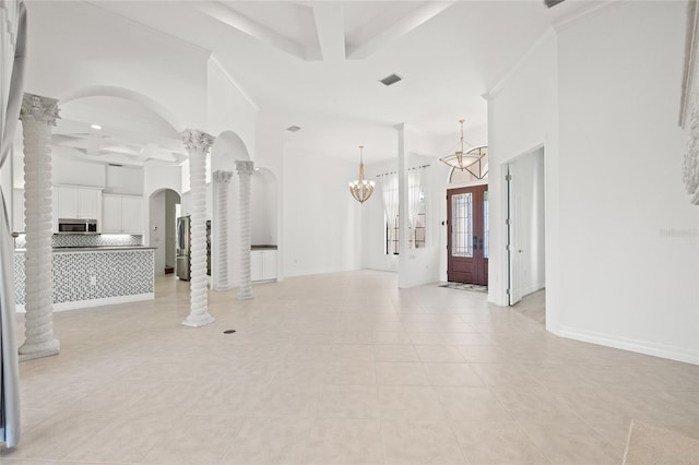 tiled entryway with ornamental molding, ornate columns, and a notable chandelier