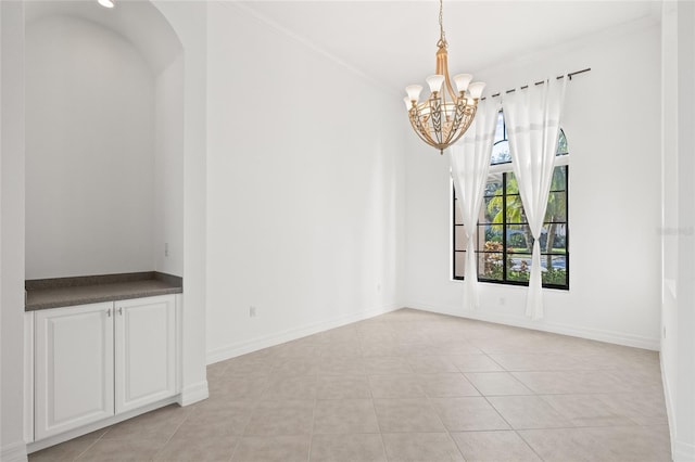 tiled spare room with a notable chandelier and crown molding