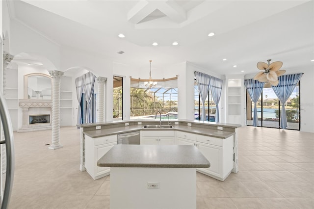 kitchen featuring a center island, sink, light tile patterned floors, decorative light fixtures, and white cabinets