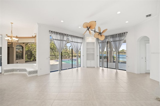 tiled spare room with ceiling fan with notable chandelier, a water view, ornamental molding, and a wealth of natural light