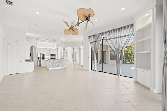 unfurnished living room with ceiling fan with notable chandelier, light tile patterned floors, and built in shelves