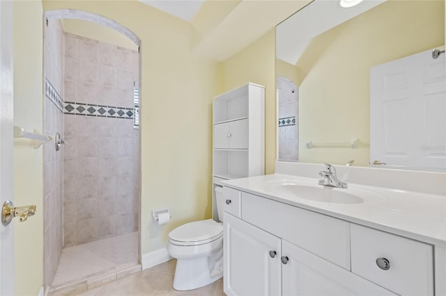 bathroom featuring tile patterned flooring, vanity, toilet, and tiled shower