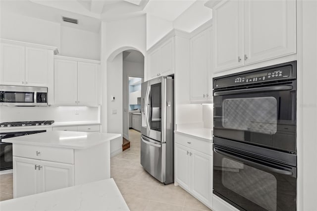 kitchen featuring white cabinetry, appliances with stainless steel finishes, light tile patterned flooring, and light stone counters