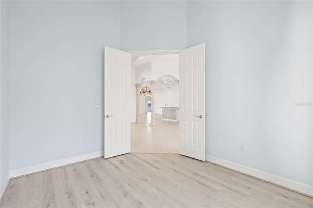 spare room with a high ceiling and light wood-type flooring